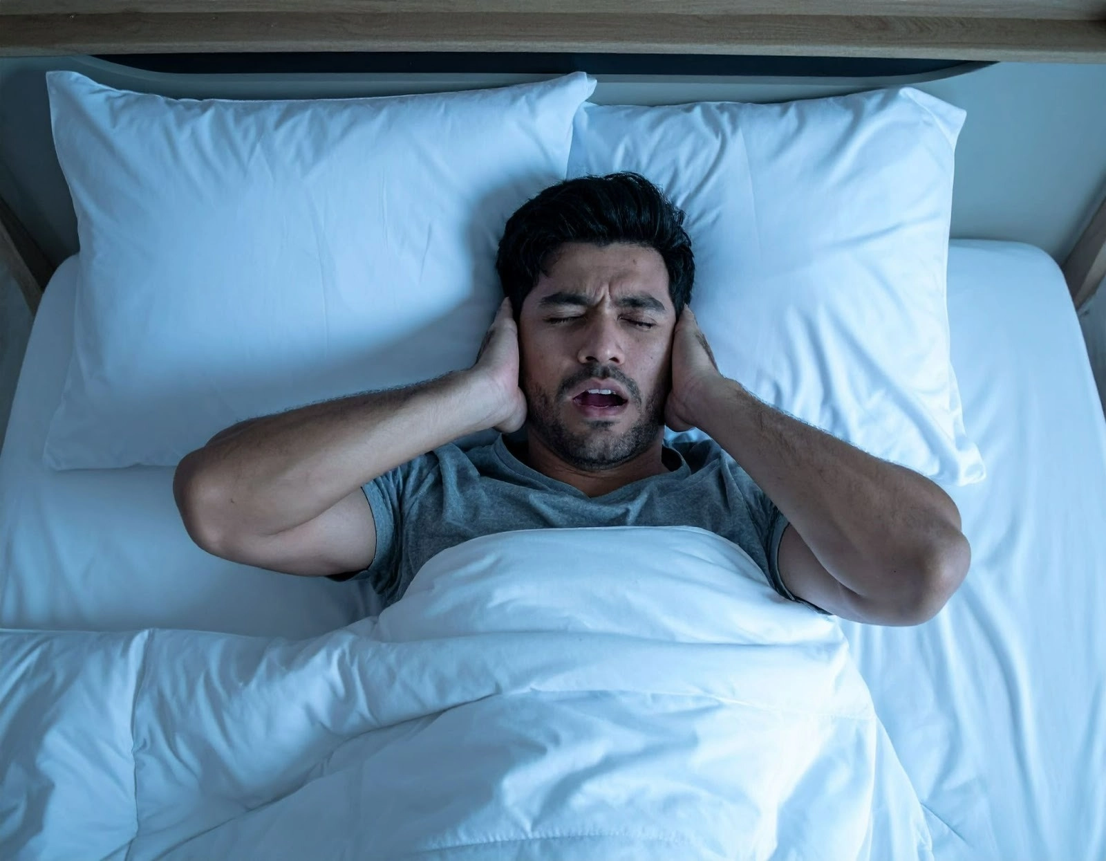 夜晚臥室內清楚聽見鄰居聲響,屋主躺在床上摀住耳朵,沒睡飽而表情痛苦