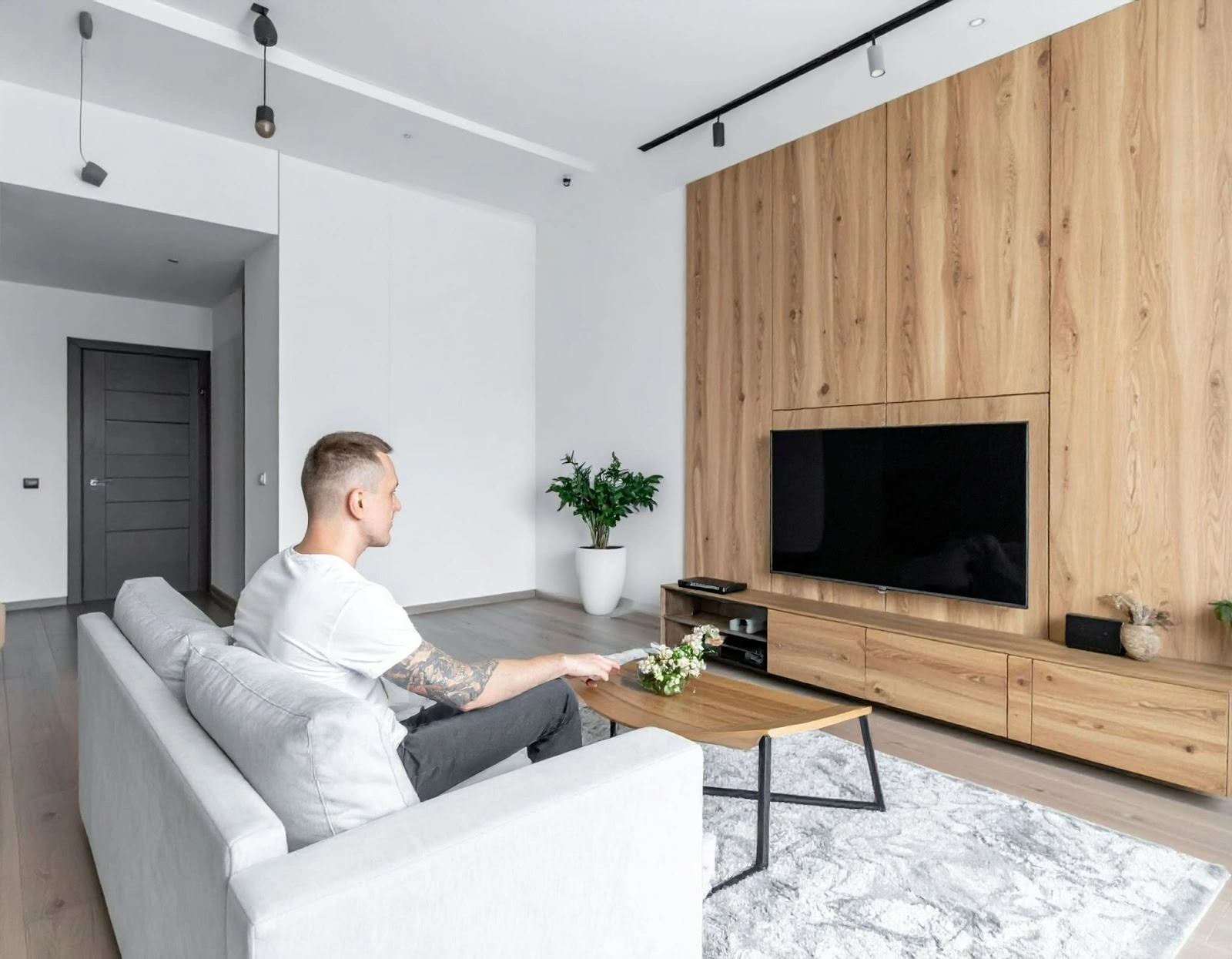 屋主坐在沙發上觀看電視小坪數客廳的北歐風電視牆