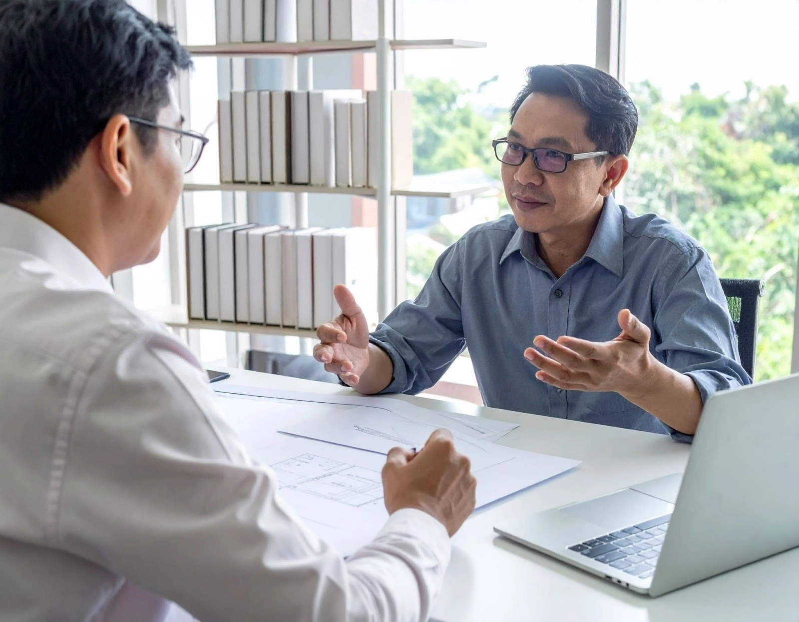 亞洲人設計師在辦公桌前向屋主解說裝修保固條款